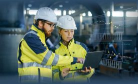 people in ppe looking at a laptop in an industrial setting